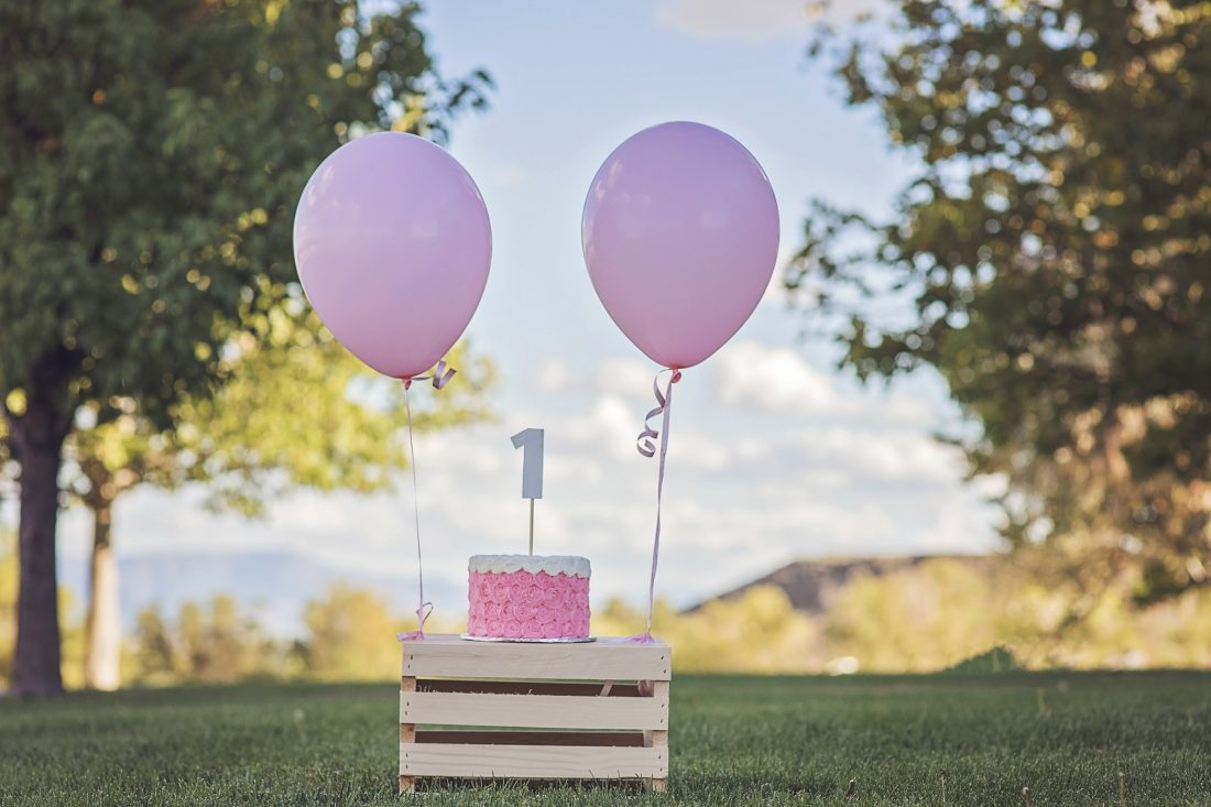 Foto eines Geburtstagskuchens mit einer "1" und zwei Luftballons (https://isorepublic.com/wp-content/uploads/2018/11/birthday-balloons-1100x733.jpg)