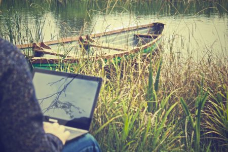 Man on Laptop with Boat