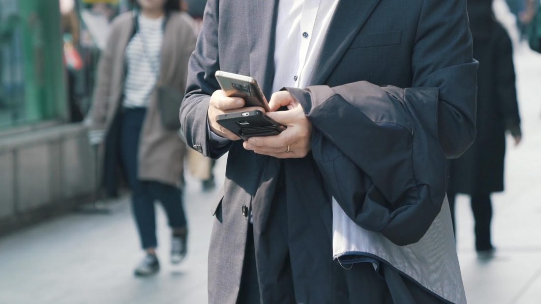 Man Using Two Mobile Device